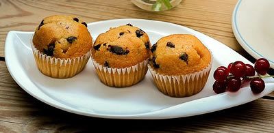 3 muffins on a leaf shaped white plate with a small bunch of berries on the right hand side