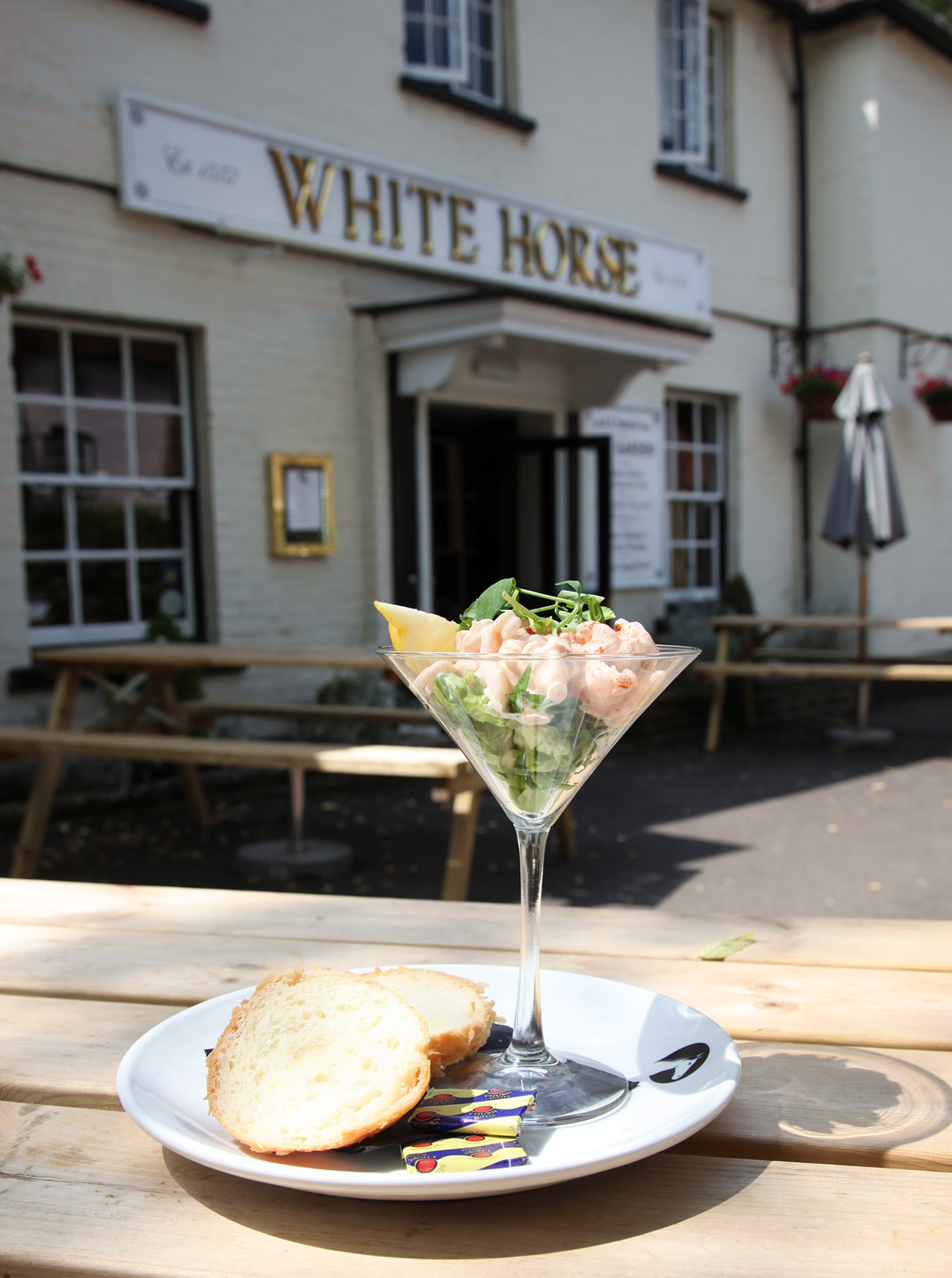 Lunch at the White Horse. Prawn cocktail served in a glass on a tablein the sunshine in front of the 16th century pub