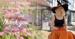 On Location In a Real Village Street and Thank You. Left side, woman's hand touching a flower fading into right side with cozy author Holly Bell sitting on a wooden table in front of a 400-year-old English pub