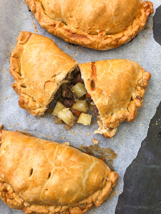 Three Cornish pasties. One cut in two to show meat and potato filling