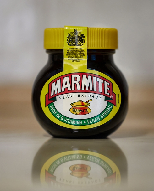 A jar of Marmite on a reflective surface.