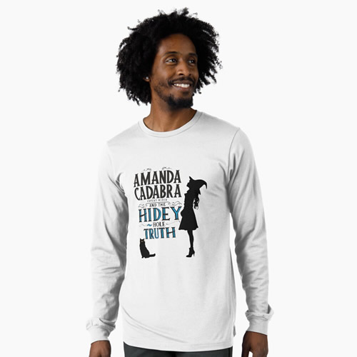 White long sleeve . On the front: Amanda Cadabra and The Hidey-Hole Truth text with silhouette of Amanda in witch hat  looking up, on the right of the text, and silhouette of Tempest, her cat and familiar opposite her feet below and on the left of the text 