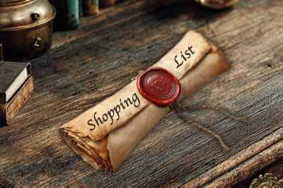 Sealed parchment scroll with the words Shopping List on it on a vintage wooden desk.