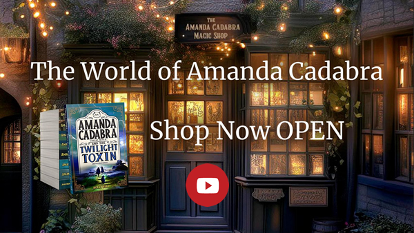 Click to go to video. Cosy magical shop, orange light coming from door and window, glwoing in the dark, lights all around. Text: The World of Amanda Cadabra. Shop now Open.On Redbubble