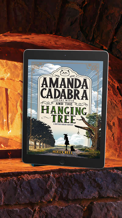 Free book on 25th October 2026: Amanda Cadabra and The Hanging Tree by Holly Bell. Cover: A silhouette of a young woman in witch's hat is looking towards a rope hanging from a tree branch to her right.There is a grumpy grey cat at her feet. She is the in middle of an avenue of trees under blue sky with white clouds
